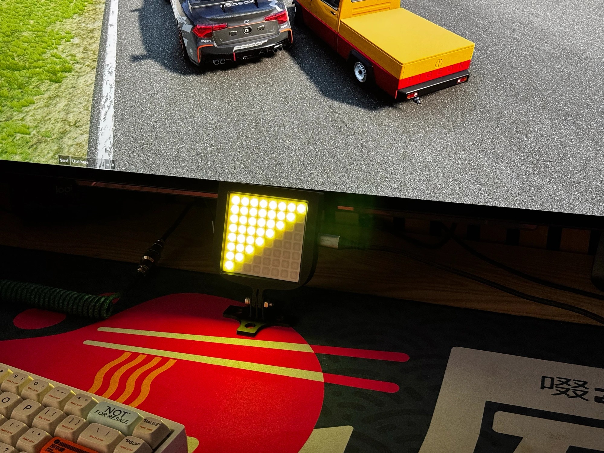 iFlag: GT Edition mounted below a sim racing monitor, displaying a live yellow caution flag on its 8x8 LED matrix while a race plays on screen