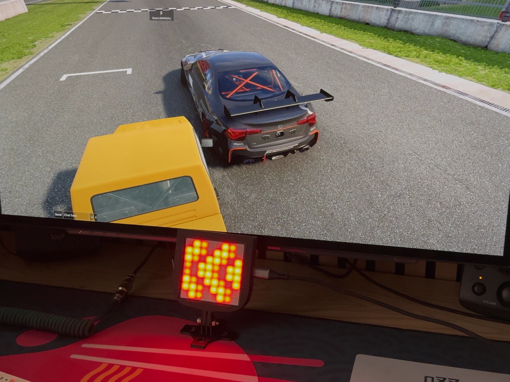 iFlag: GT Edition in use below a sim racing monitor, displaying a flag pattern in red and yellow LEDs during a race