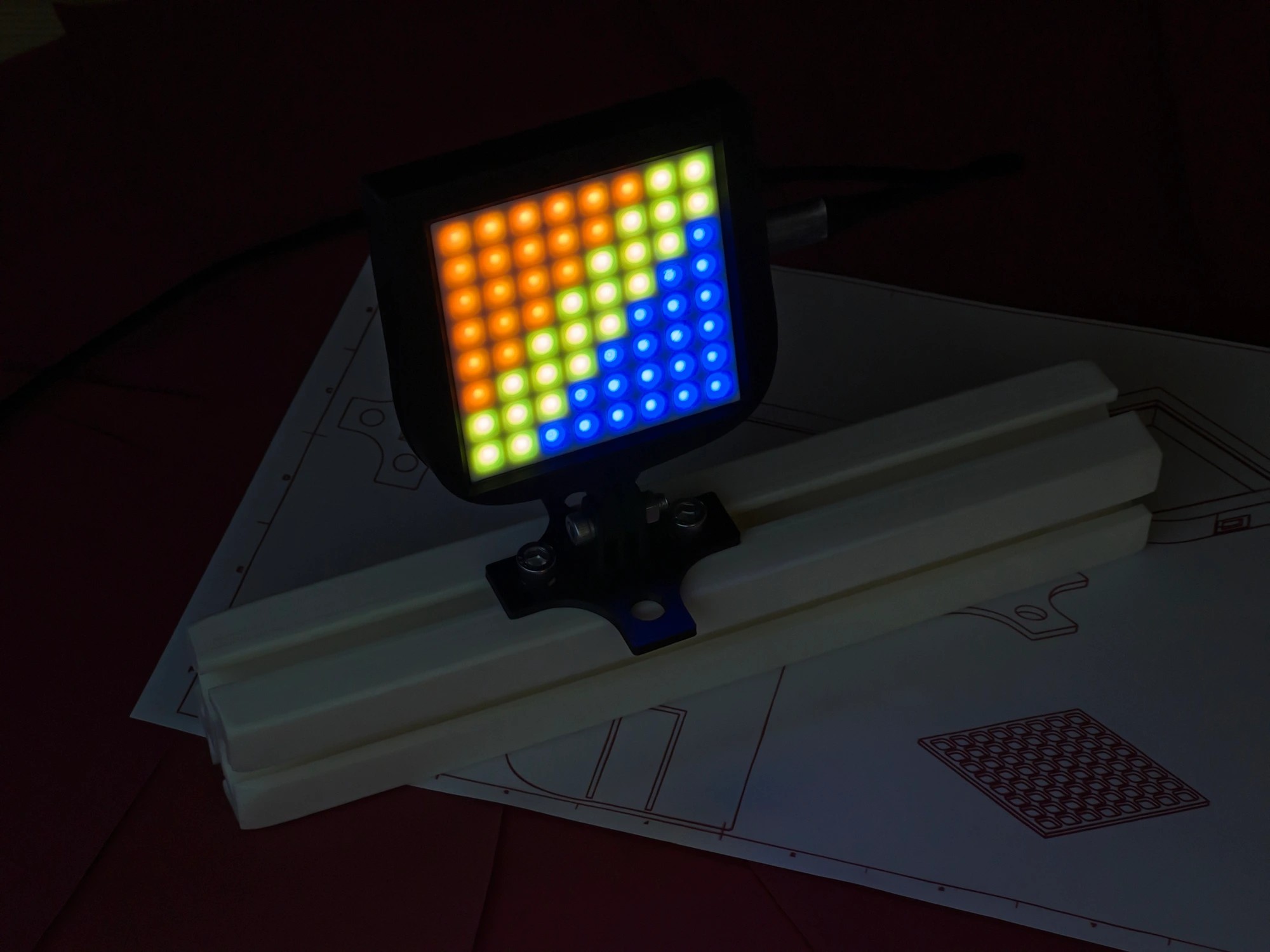 iFlag: GT Edition showing a full-colour RGB pattern on its 8x8 LED matrix - orange, blue, green and white - mounted on aluminium extrusion, demonstrating the fully customisable ARGB LEDs