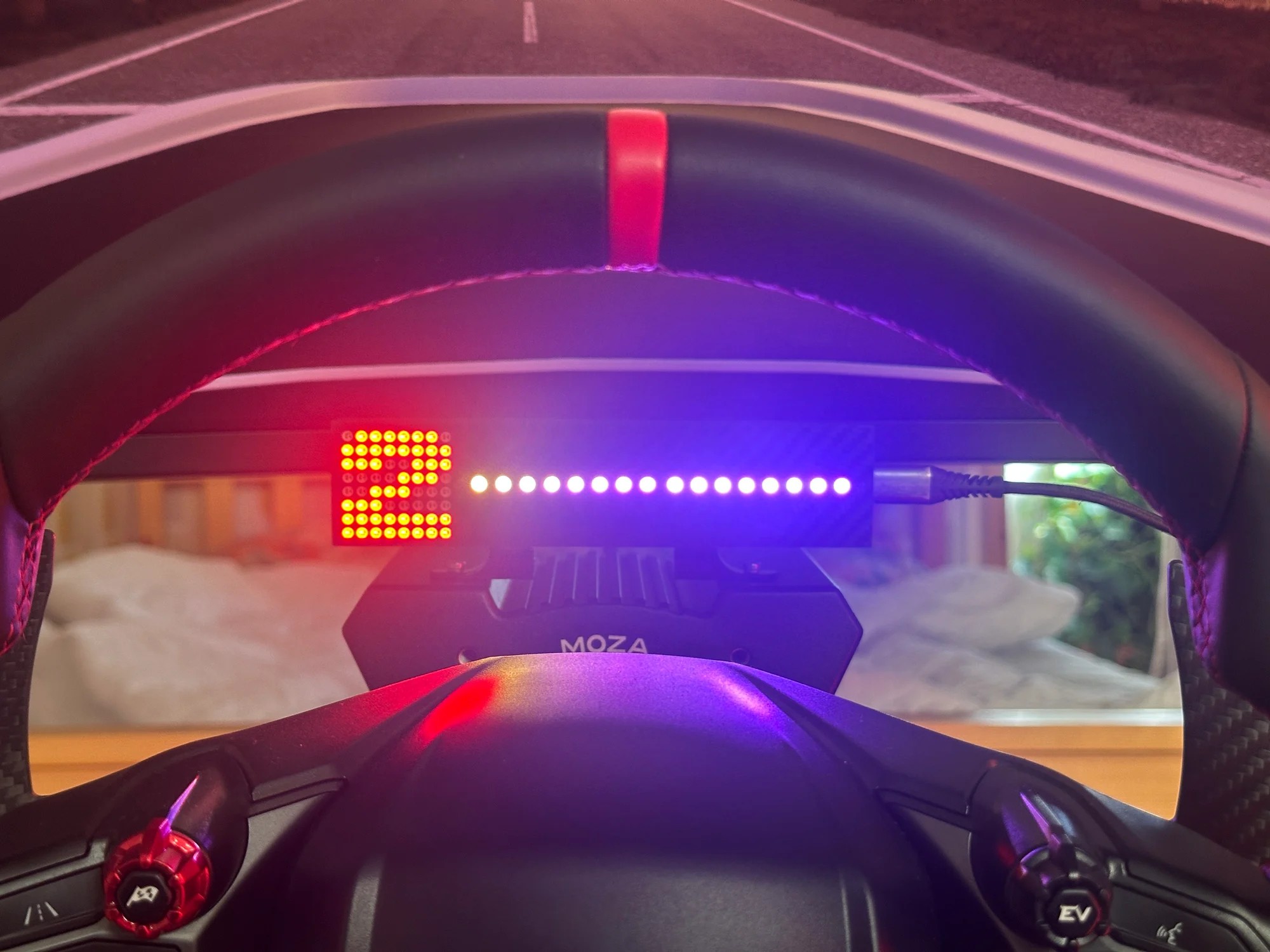 The dashboard seen through the top of the steering wheel mid-race, gear and shift lights readable at a glance