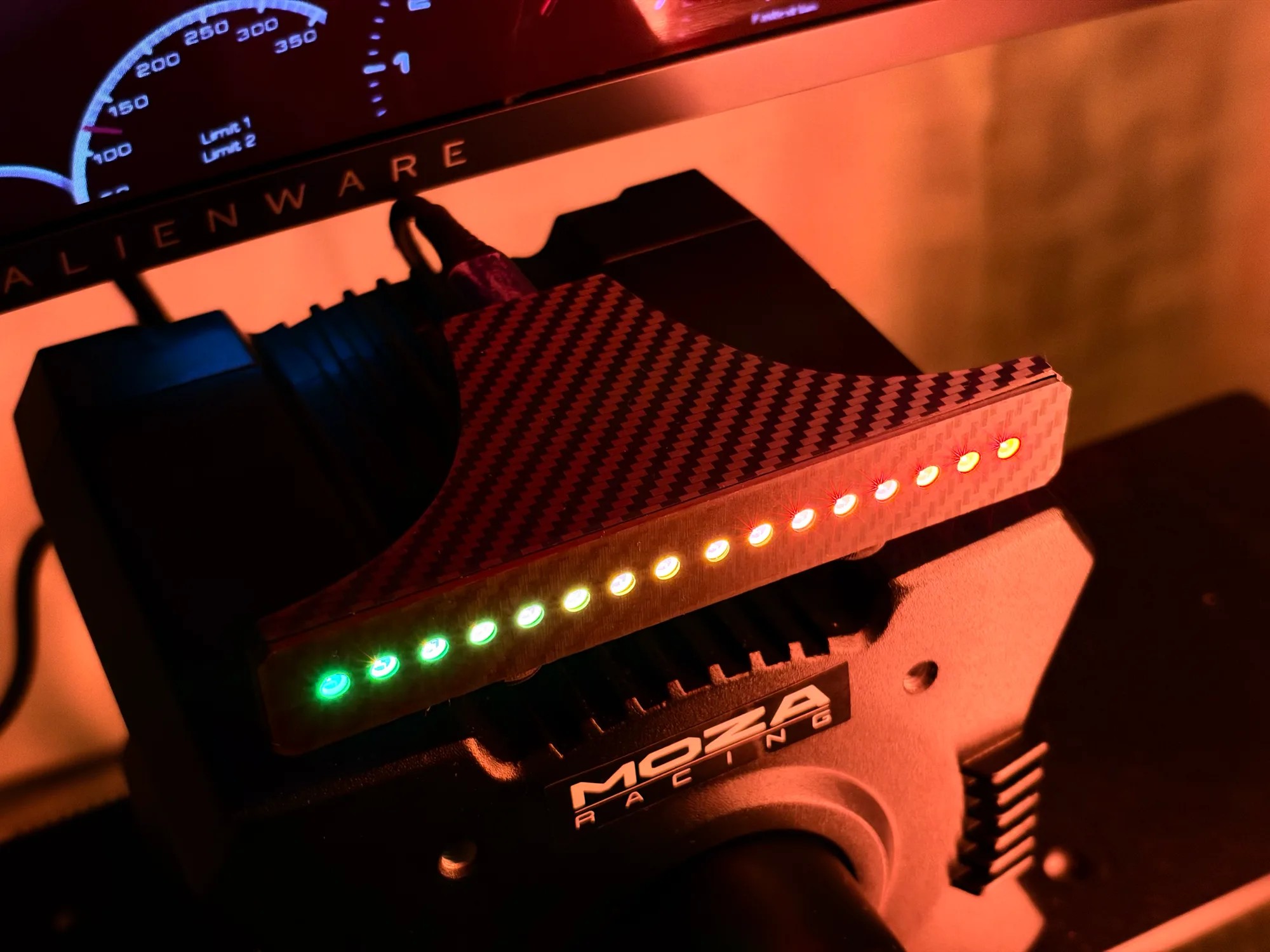Shift Lights Pro on a MOZA wheelbase seen from the side, lit green through amber, the carbon-effect face catching the light
