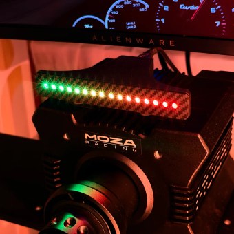 Shift Lights Pro on a MOZA wheelbase, lit green through amber to red across all 16 LEDs, with the rev counter on the monitor behind it